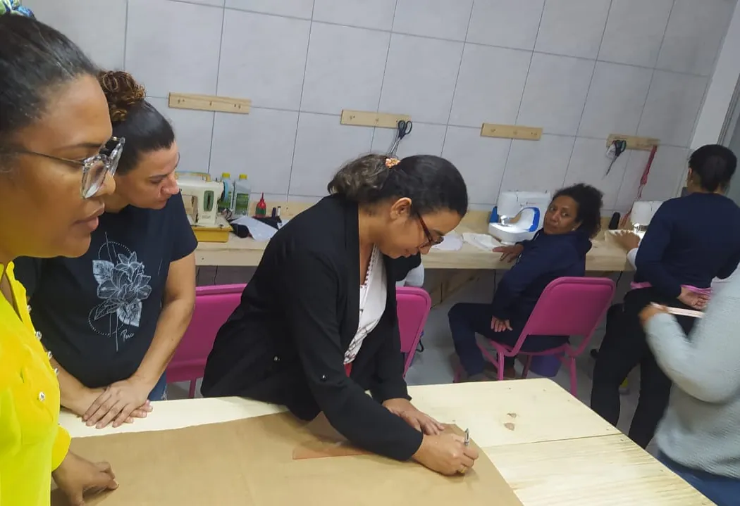 Aula de corte e costura no Instituto: a professora e as alunas trabalham juntas na mesa de modelagem