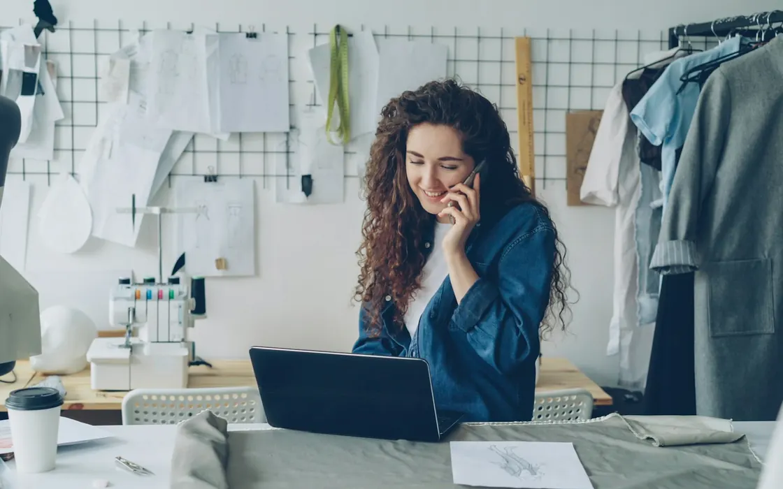 Empreendedora ao telefone no seu ateliê de costura
