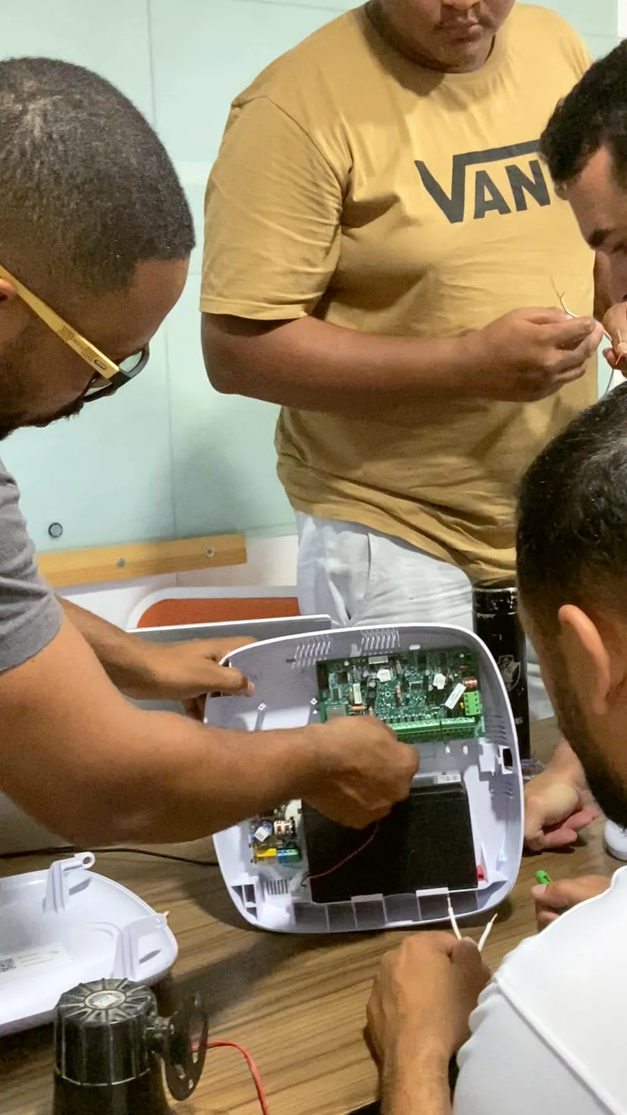 Aula prática de eletrônica: mãos de alunos montam um circuito sobre a bancada
