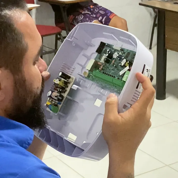 Aluno examina a placa de circuito na aula de eletrônica