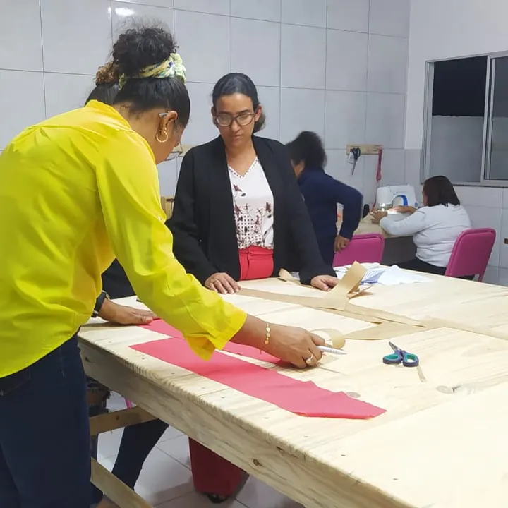 Professora acompanha a aluna na mesa de corte
