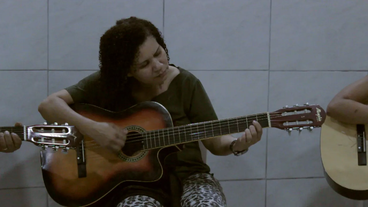 Aluna tocando violão durante a aula de música